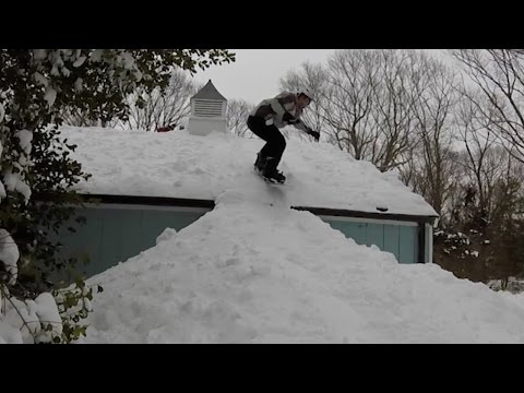 يتزلج على سطح بيته بعد أن غطته الثلوج
