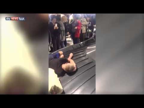 بالفيديو مسافر ينام على مسار الحقائب في المطار