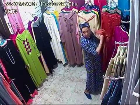 امرأة تسرق عباية من أحد محلات الملابس