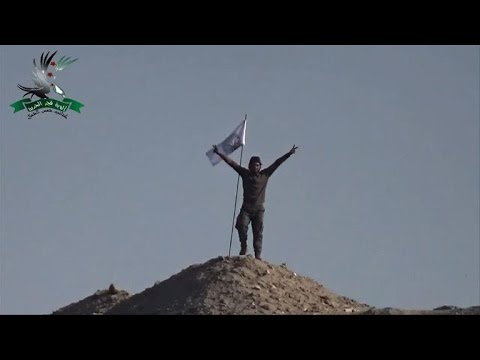 syrian rebels and kurdish flags on a hill